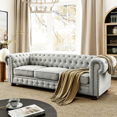 3 places gris luxueux avec revêtement en lin, accoudoirs à volutes et détails cloutés, convient aux espaces de vie dans la décoration de bureau