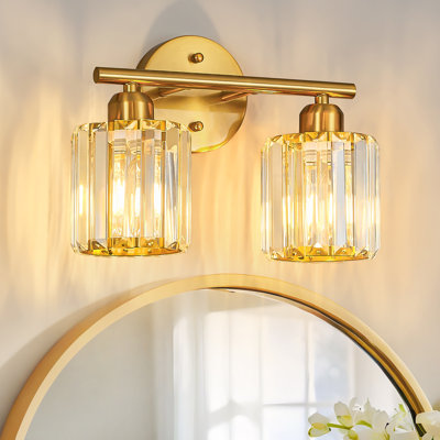 Applique murale verticale Kyneisha moderne en or brossé à 2 lumières avec cristaux, à placer au-dessus du miroir de la coiffeuse ou du lavabo. Compatible avec les ampoules à intensité variable (ampoules non comprises).