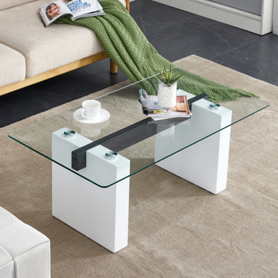 Table basse moderne en verre trempé transparent minimaliste, jumelée à des colonnes décoratives en panneau de fibres à densité moyenne blanches. Bureau d'ordinateur. Table de jeu