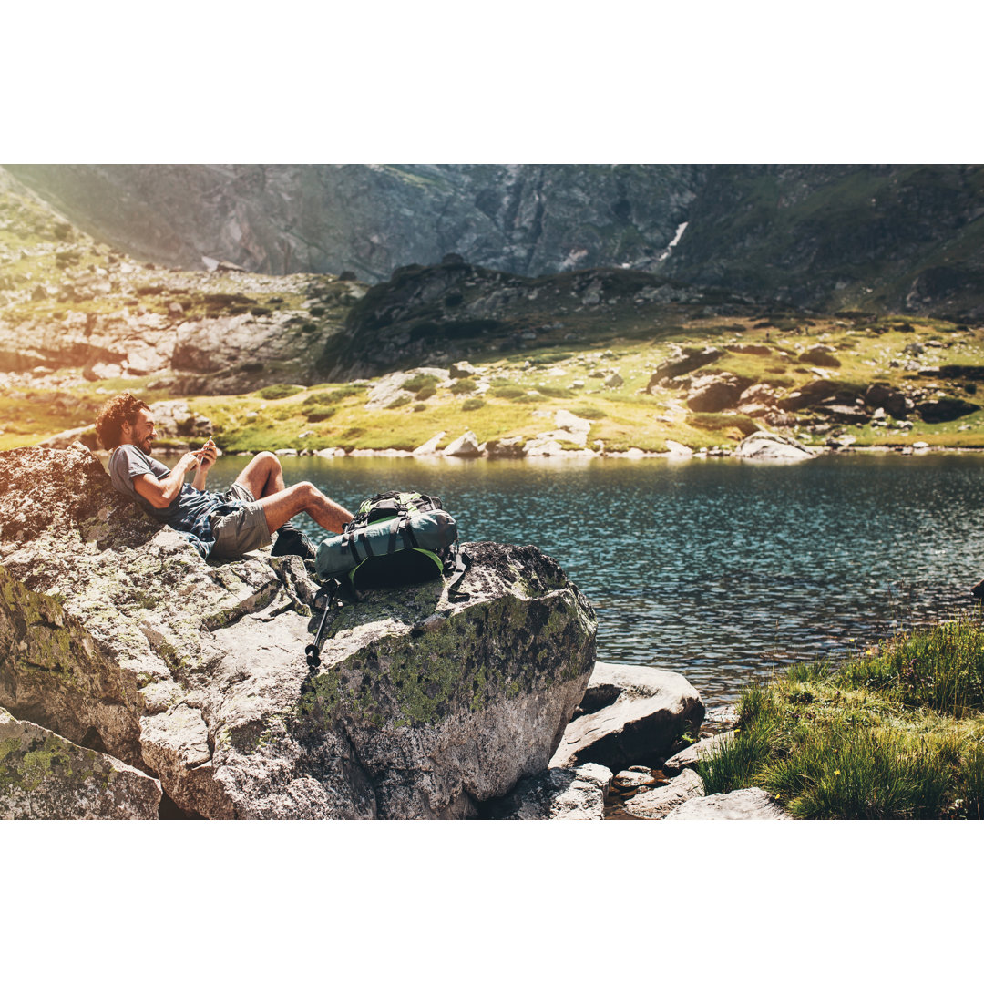 Solo Traveler Lying On A Rock And Texting by Pixelfit - No Frame Set on Canvas