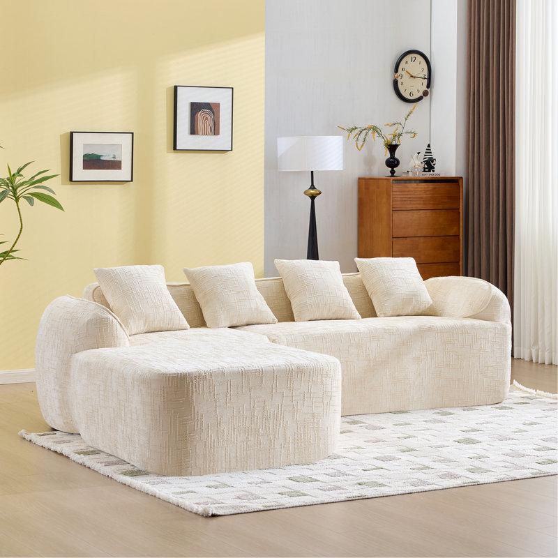 Canapé en forme de L beige en chenille qui s'agence bien avec n'importe quel salon. Il est doté d'une éponge hautement élastique pour une sensation d'assise confortable, d'accoudoirs courbés et de quatre coussins décoratifs.