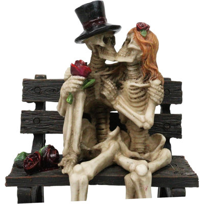 Figurine squelette avec un chapeau haut de forme et une perruque assis sur un banc de parc avec des roses