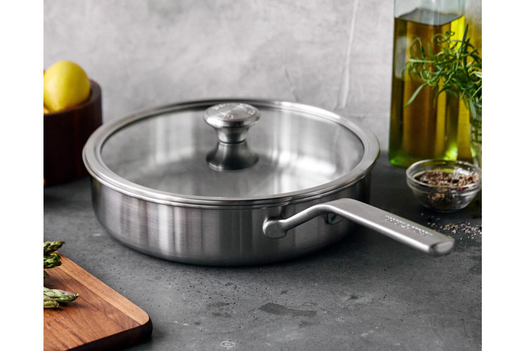 stainless steel saute pan on a granite counter next to fresh herbs