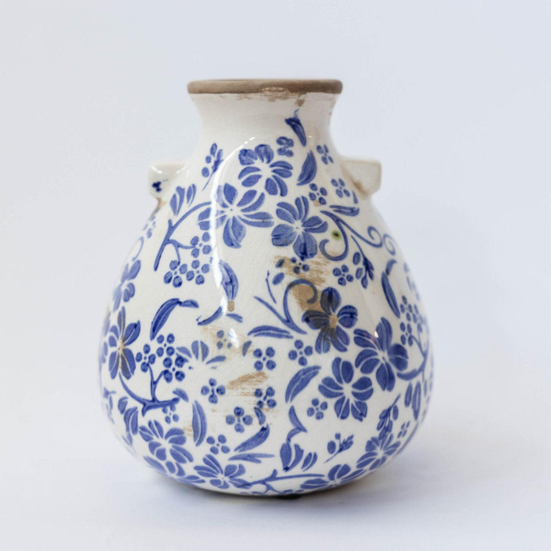 Motif floral bleu sur vase blanc rustique