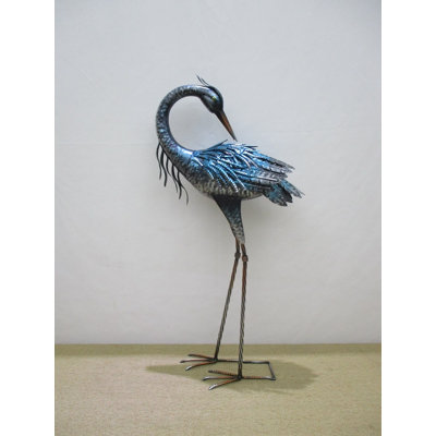 Sculpture grue bleue derrière un jardin