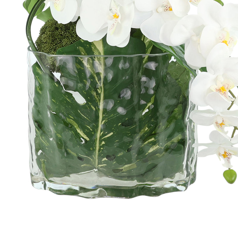 Arrangement d'orchidées avec philodendron dans un vase