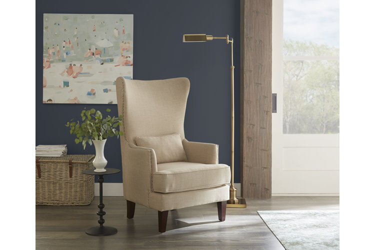 wingback accent chair with a small round side table and a gold floor lamp