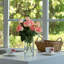 Fleurs artificielles en soie rose dans un vase en verre transparent avec de l'eau artificielle-1247399433