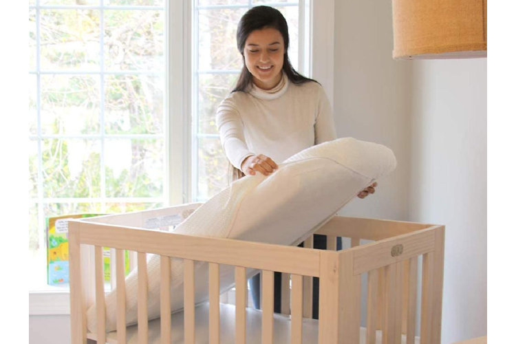 Placing a mattress in a crib.