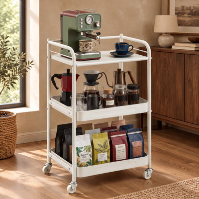 Un support à roulettes en métal blanc à 3 niveaux sert également de support à fruits et légumes, d'organisateur de collations ou de station de café, avec un plateau de table et des étagères à panier