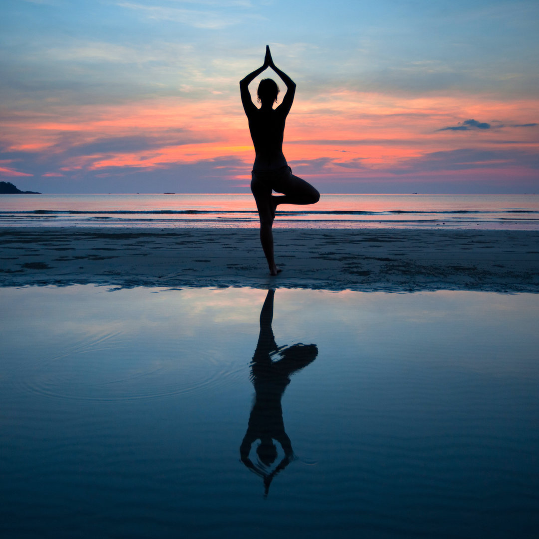 Leinwandbild Junge Frau übt Yoga bei Sonnenuntergang an der Küste