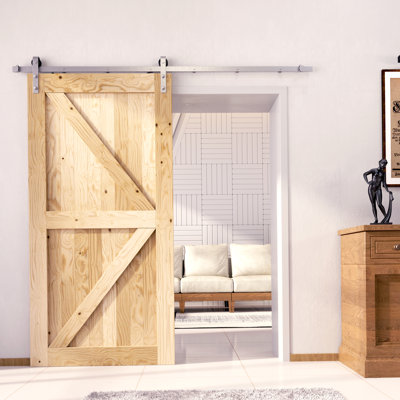 Une porte de grange en bois de pin massif non fini / non assemblé avec une quincaillerie d'installation en nickel brossé