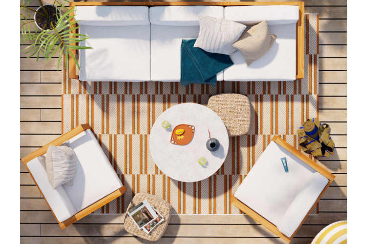 deck with an orange and white striped rug under an outdoor living space with a white sofa, coffee table, and accent chairs.