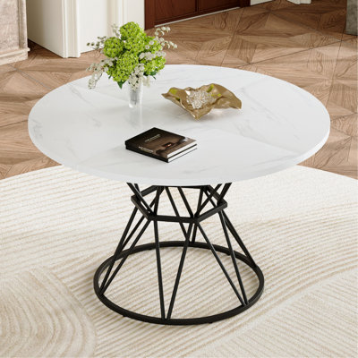 Une table de salle à manger circulaire d'un diamètre de 47,3 pouces, composée de 4 panneaux de fibres à densité moyenne à motif de marbre blanc, de supports en métal en forme de sablier noir et d'une table de salle à manger de style industriel moderne pour 4 à 6 personnes.