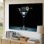 Toile Un élégant verre à martini moderne se dresse élégamment sur une surface d'art murale lisse illuminée sur un fond noir profond-558922632