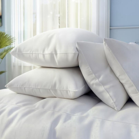 Two white pillows on a small table next to a basket of linens.