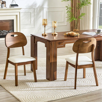 2 chaises de salle à manger en bois massif de couleur noyer, des coussins de siège souples en polyuréthane blanc, des dossiers évidés et des chaises de salle à manger.