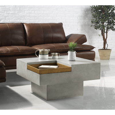 Table basse en ciment de style rustique avec plateau carré et piédestal sur fond gris patiné