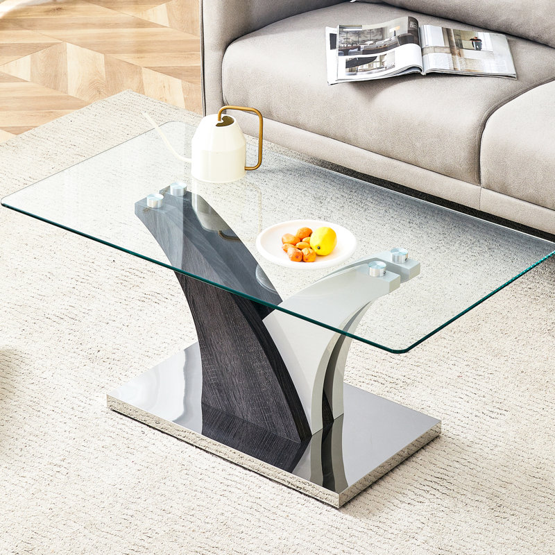 Table basse rectangulaire en verre avec pattes stables et design artistique dans les tons gris et blanc. Élégant plateau transparent.