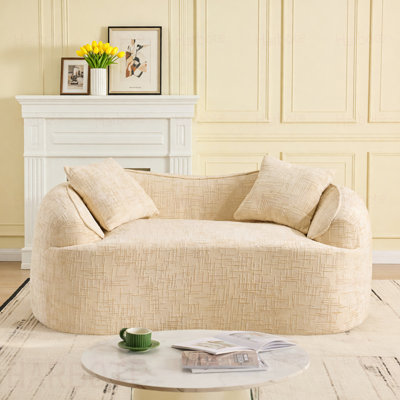 Beige Curved two - person compress sofa. It has armrests on both sides, comes with two pillows, is  for small - sized apartments