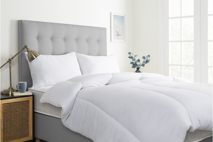 coastal bedroom with white walls, a gray tufted bed, and a white duvet