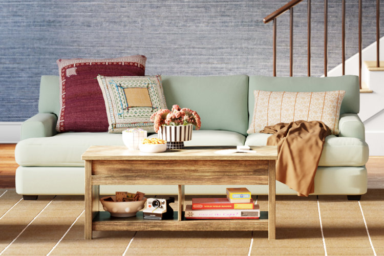 blue mid-century modern three-seat sofa with a picture ledge, industrial-style floor lamp, and layered area rugs