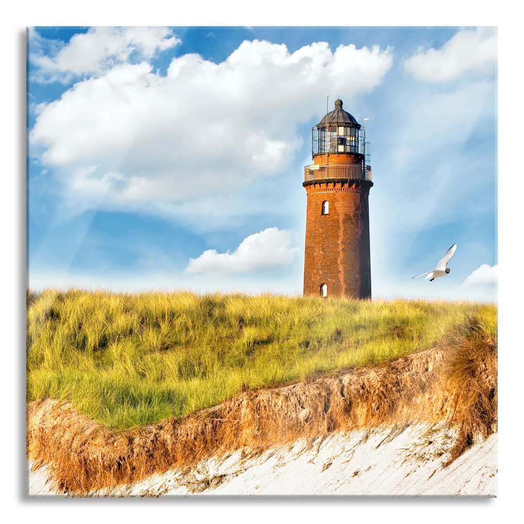 Glasbild Möwen fliegen am Meer vor einem Leuchtturm