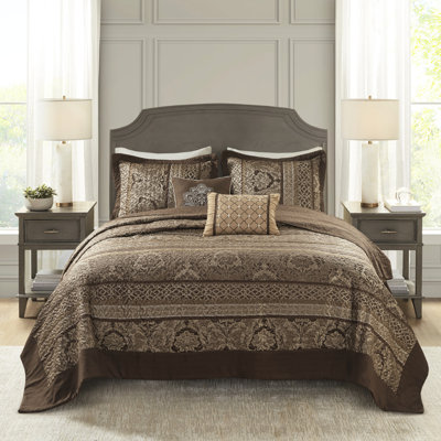 Grand couvre-lit réversible - 5 pièces. Brun et or. Comprend un couvre-lit, 2 taies décoratives et des coussins décoratifs. Fabriqué à partir d'amende pour un luxe durable. Expositions de feuilles, rayures, motifs. Décoré avec des coutures.
