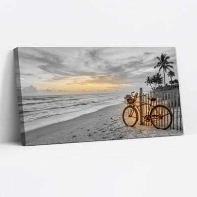 Tableau sur toile représentant un vélo vintage appuyé contre une clôture de plage en bois