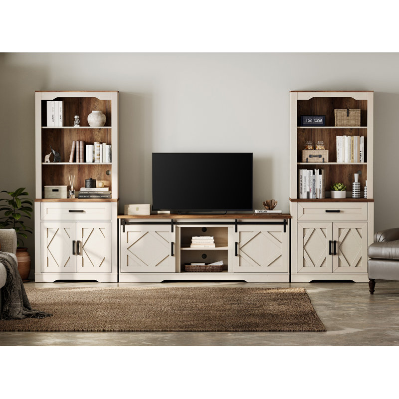 Farmhouse entertainment center in white and brown wood with a central sliding barn door TV stand flanked by two tall matching bookshelves.