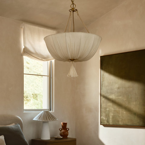 Hanging tasseled chandelier in neutral bedroom.