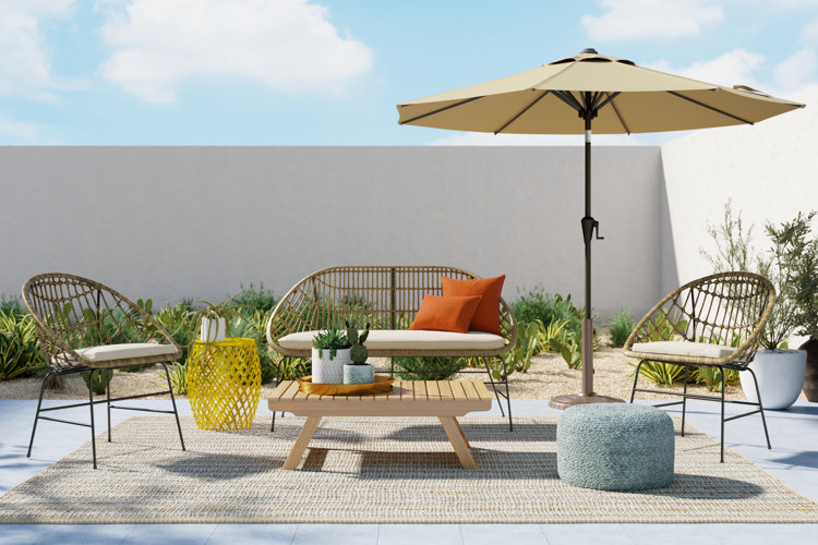 boho patio with a wicker patio conversation set, patio umbrella, and a braided jute pouf