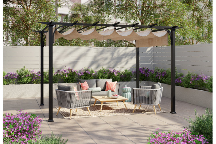 A patio with large gray square tiles, a seating area under a shaded pergola, and white fencing that encloses the patio.
