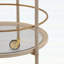 Chariot-bar rond avec tablettes en verre trempé et accents dorés, finition blanche vieillie pour une élégance moderne