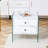 Double-Drawer Bedside Table. The Board Surface Is MDF With White Grain Sticker, And Both Sides Are Transparent Tempered Glass. The Design Is Simple And Elegant, With Excellent Storage Functions.