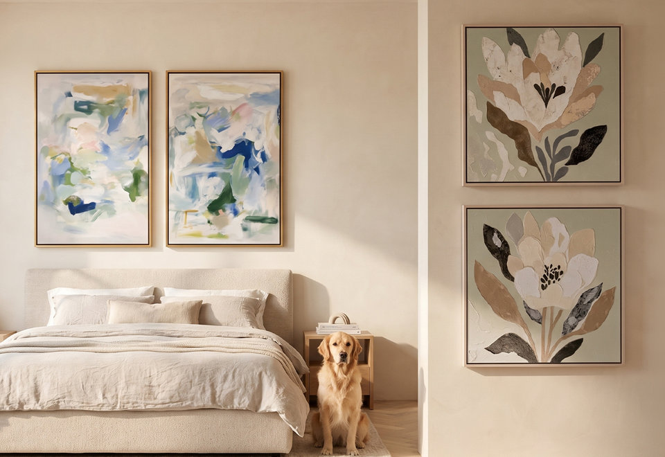 A bedroom with a beige upholstered bed and a golden retriever sitting on the floor, decorated with two abstract blue and green framed paintings above the bed and two floral textured paintings on the side wall.