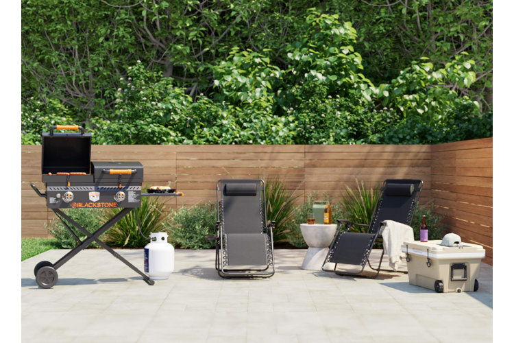 two black zero gravity chairs next to a grill on a patio