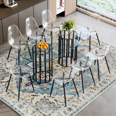 Ensemble de table et de chaises Table de salle à manger ovale en verre trempé de 71 pouces de style luxueux à double colonne noire. Jumelé avec 8 chaises en plastique transparent avec pieds en métal noir.