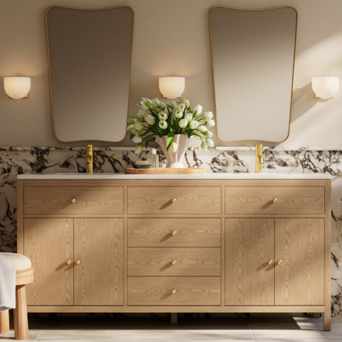Bathroom with double vanity, gold mirrors, and sconces.
