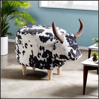Mignon repose-pieds en forme de vache avec des cornes de velours, des pieds en bouleau et un corps en tissu confortable pour un décor moderne et ludique