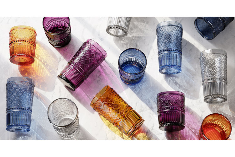 Set of drinking glasses with the same textured pattern in different colors, including blue, orange, purple, and clear.