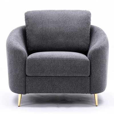 Chaise grise à dossier lâche avec revêtement en lin doux et arrondi, pieds en métal doré et intérieur en bois de pin résilient pour une assise contemporaine en tissu gris légèrement incliné.
