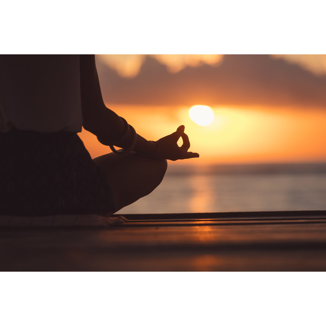 Leinwandbild Junge Frau übt Yoga am Strand