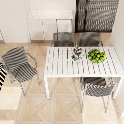 Table moderne blanche de 55 pouces avec 4 fauteuils empilables gris chaud - résistance aux intempéries, assemblage rapide, protection de forme 4, structure en métal, position assise confortable