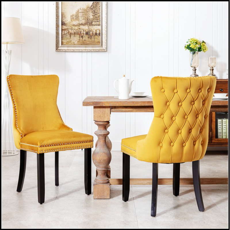 Chaise rembourrée à oreilles avec garniture cloutée et pieds en bois massif pour une assise confortable et élégante dans tout espace repas