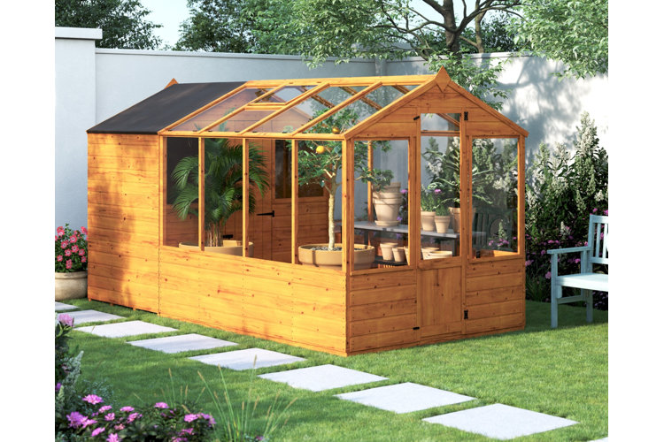Wood greenhouse in a large backyard with plenty of green grass and stepping stones.