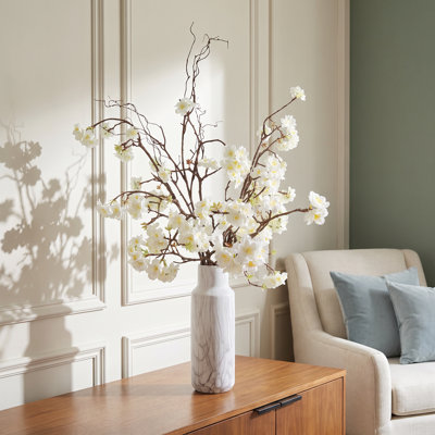 Arrangement de fleurs de cerisier et de saule dans un vase en céramique