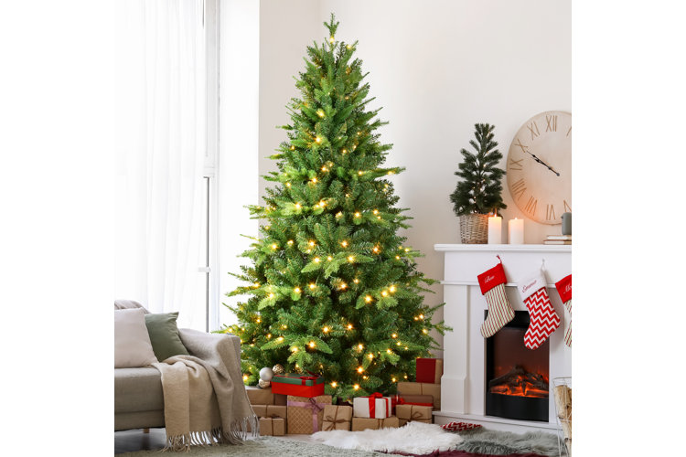 green christmas tree with white lights next to a white fireplace with gifts wrapped underneath