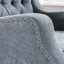 Chaise d'appoint grise avec dossier capitonné et pieds robustes, offrant confort et style pour votre maison
