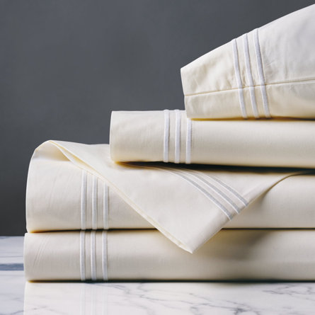 Folded cream-colored sheet set with white stripes.